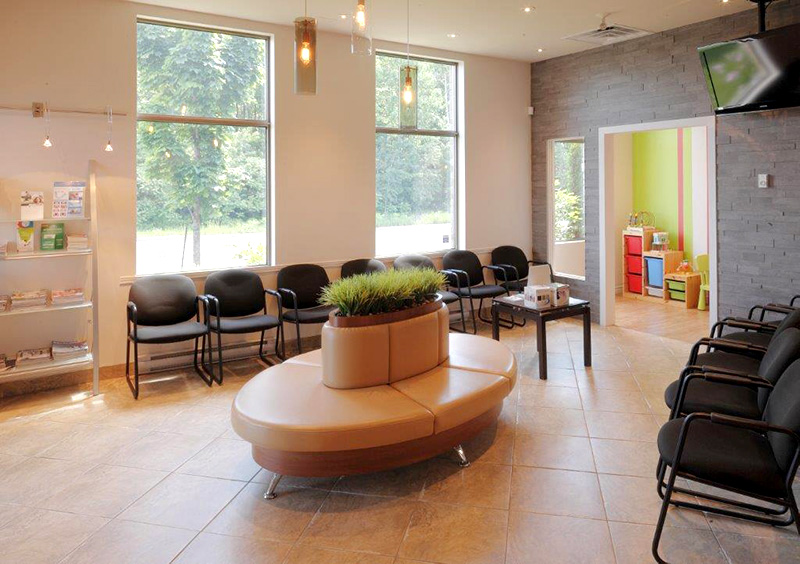 Salle d’attente lumineuse et moderne d’une clinique dentaire avec espace enfants.