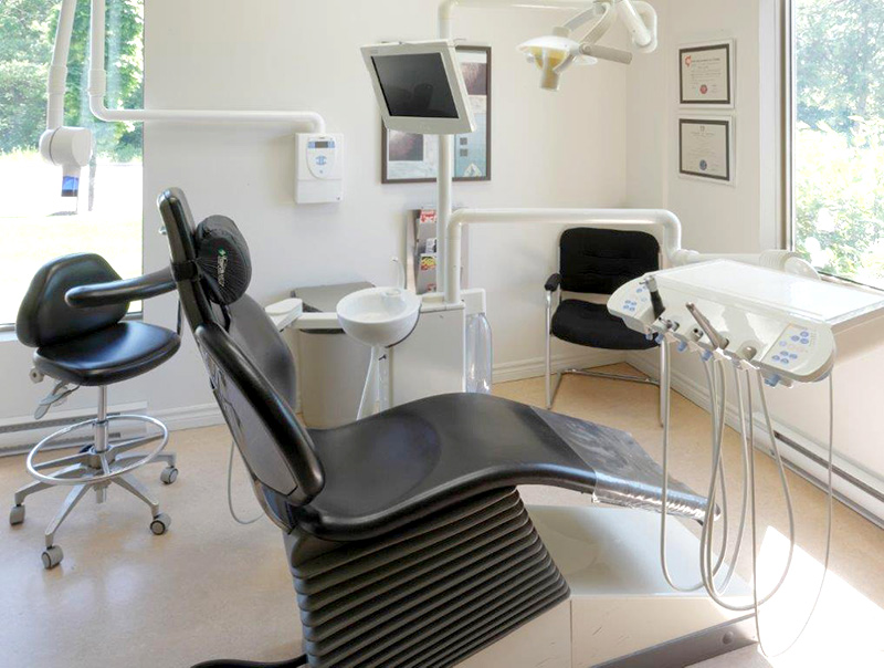 Salle de soins dentaires moderne avec fauteuil et équipements spécialisés.