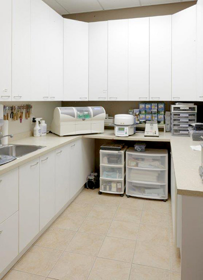 Laboratoire dentaire moderne avec équipements et armoires blanches.
